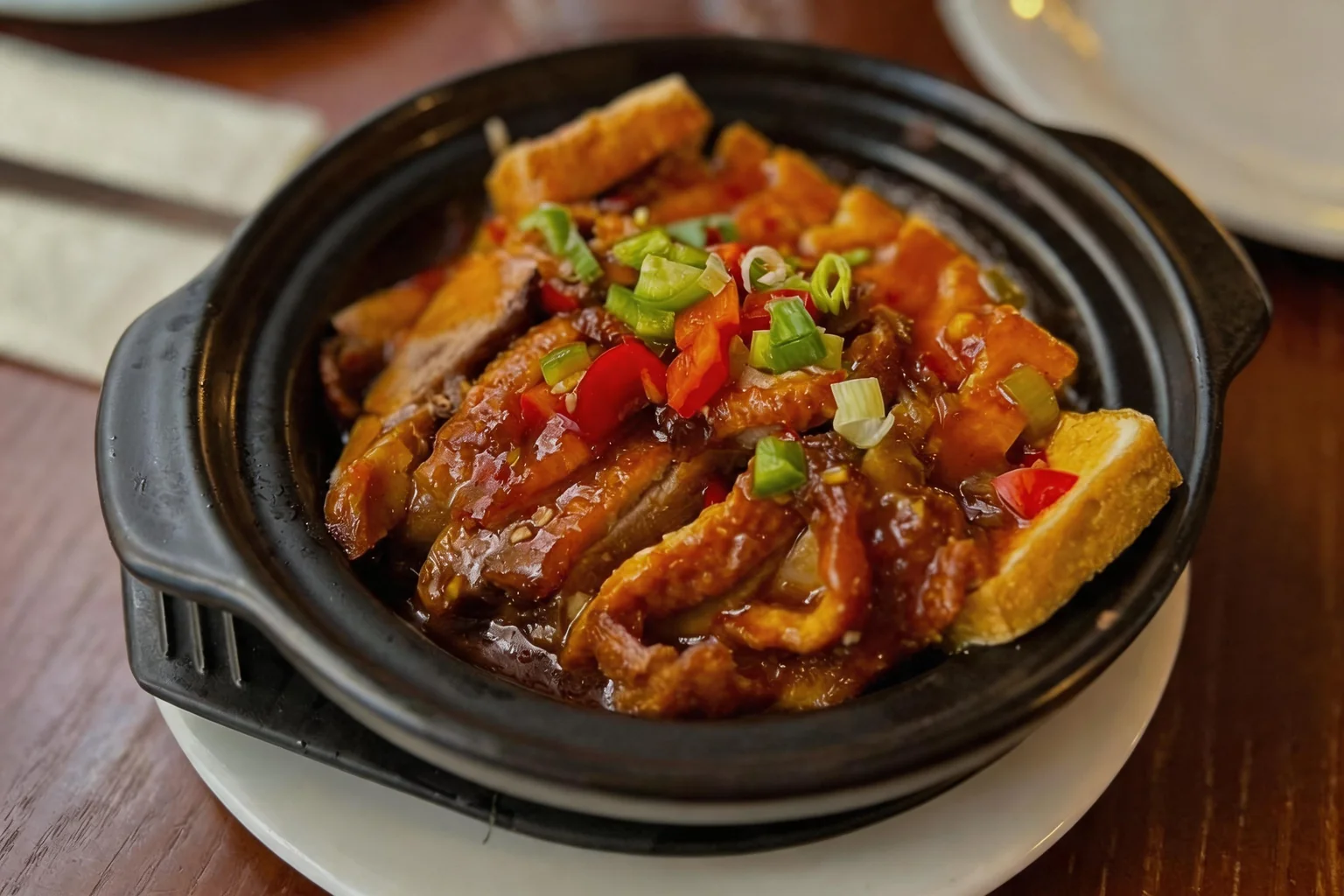 Filet de canard et tofu, sauce à l'ail, dans une marmite noire sur une table en bois