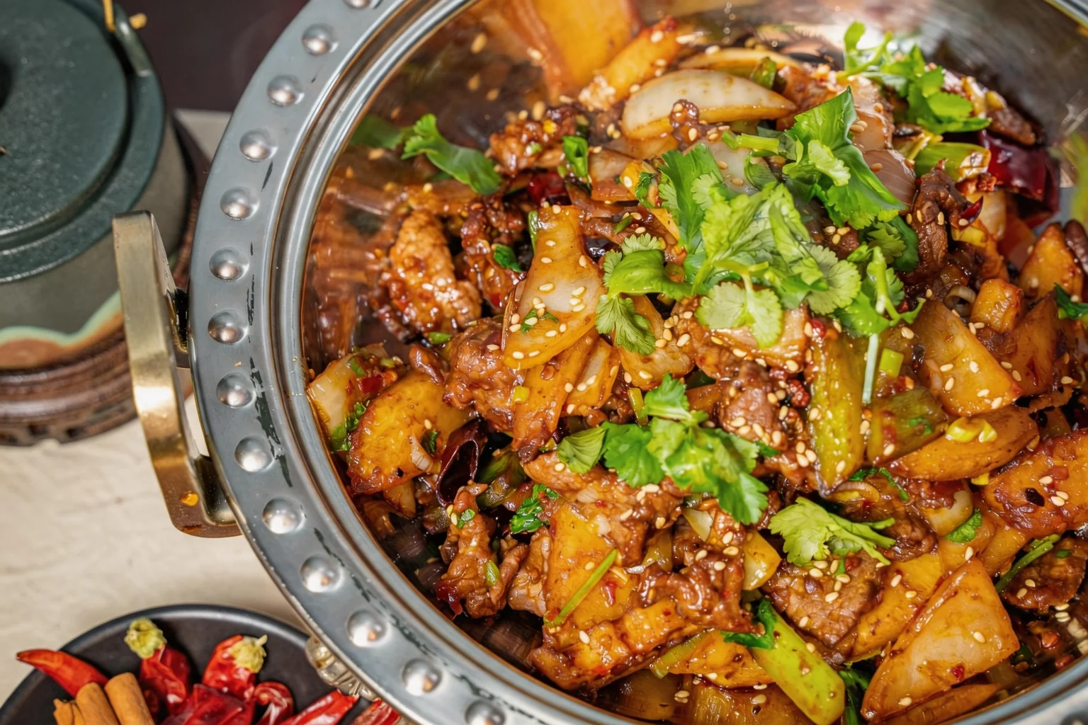 Plat dans une marmite en métal, piments séchés et cannelle à côté